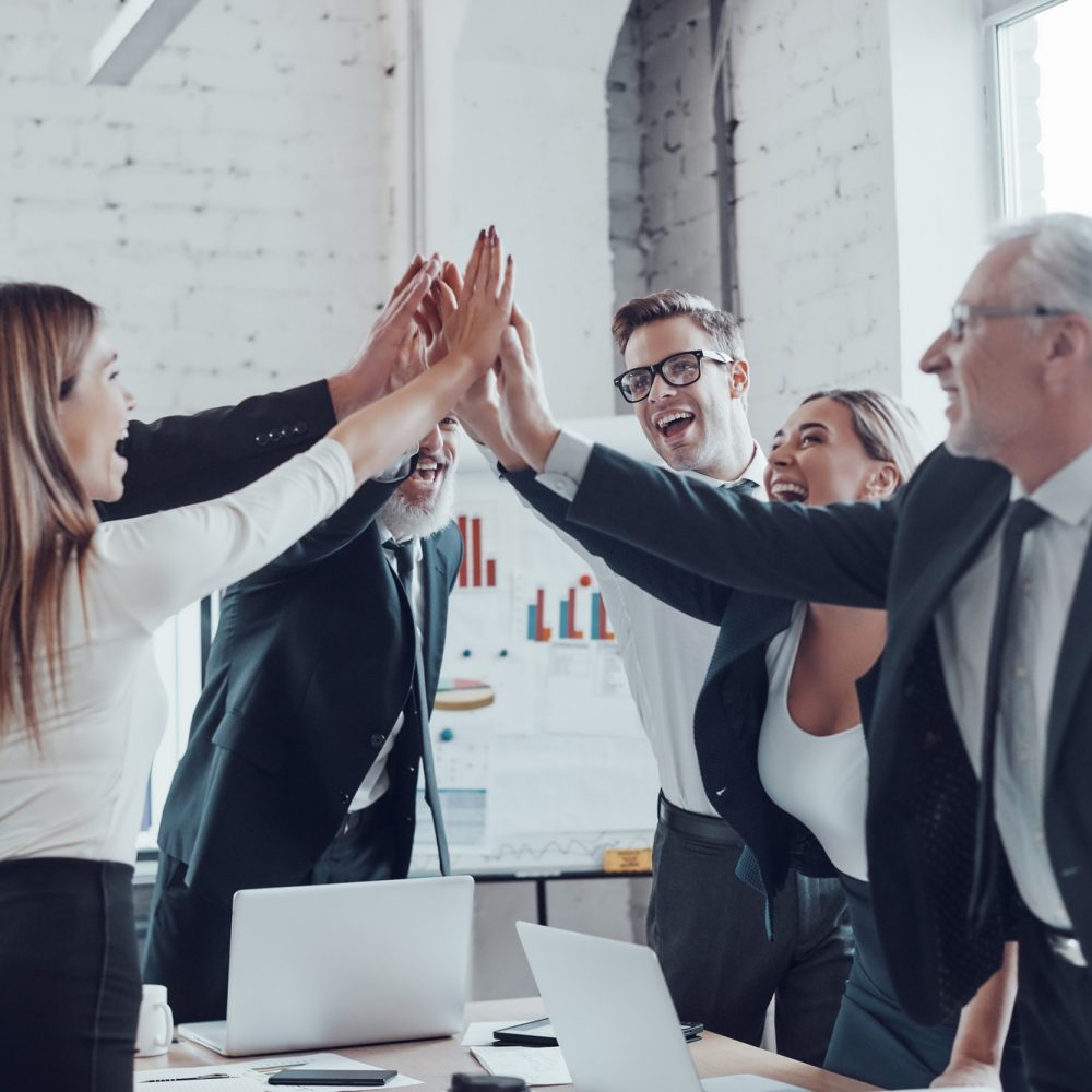 cheerful-business-team-giving-each-other-high-five-to-success-while-working-in-the-modern-office.jpg